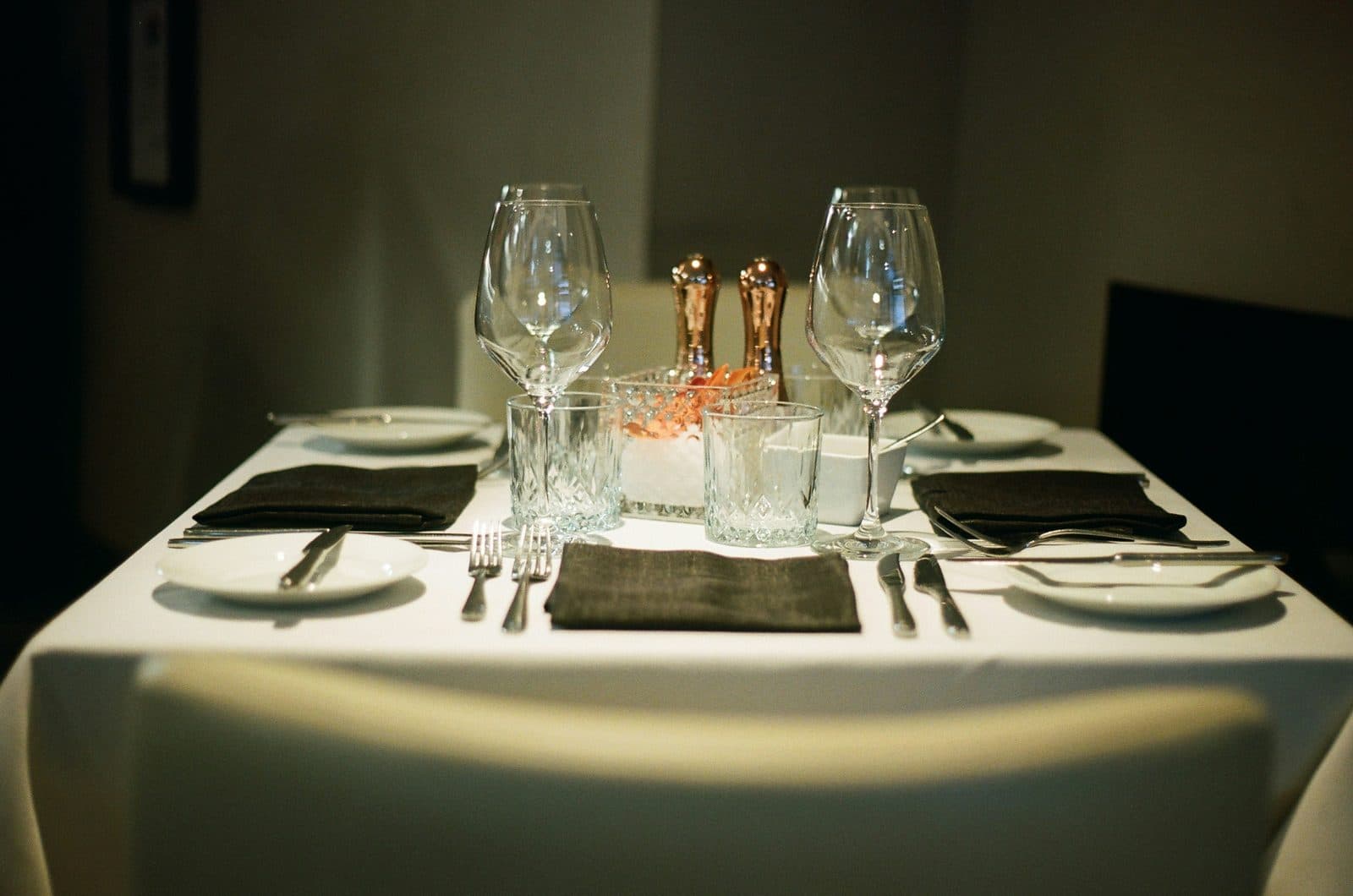 An elegantly set formal dining table with wine glasses, cutlery and folded napkins