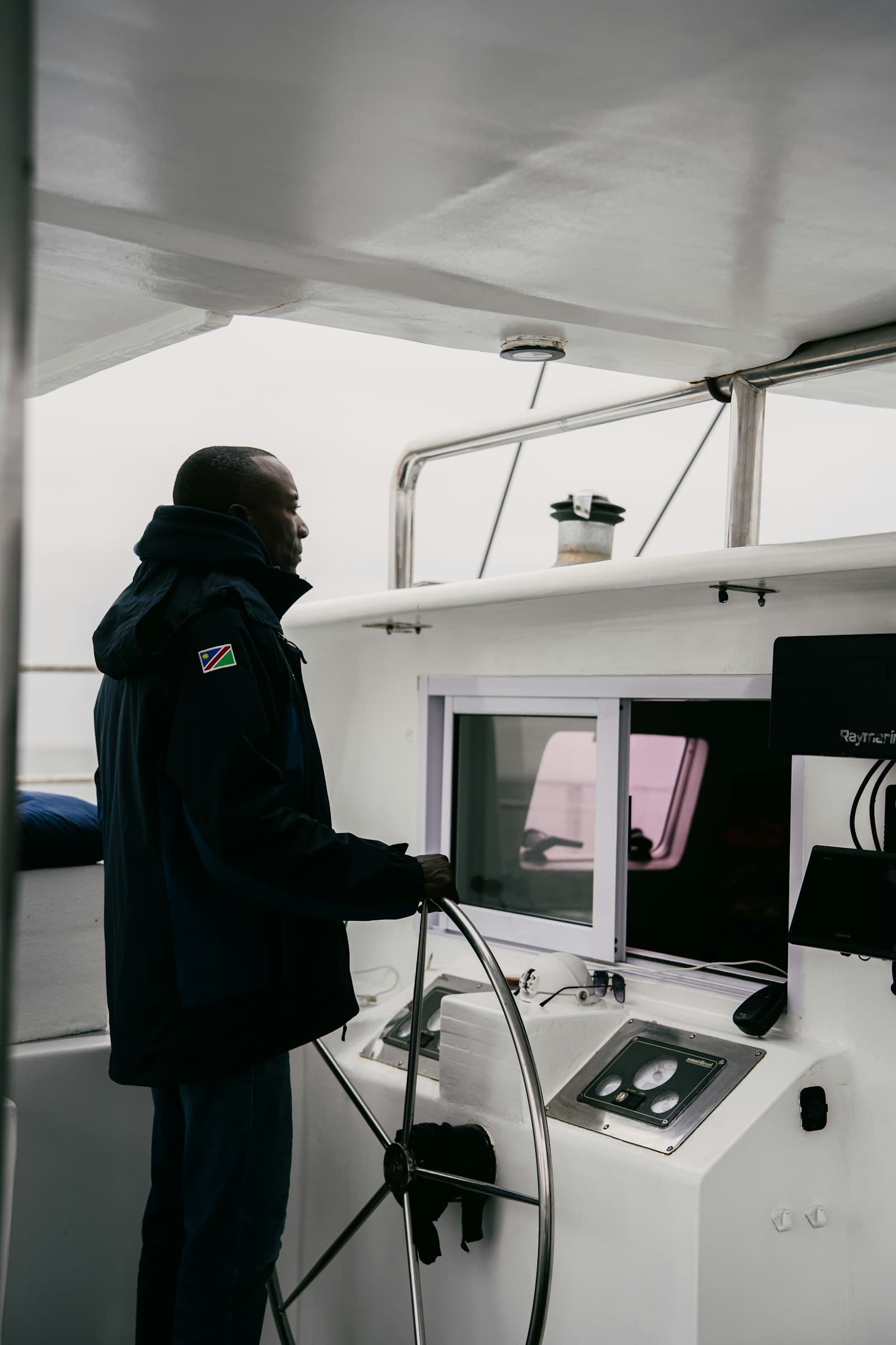 Crew member at the helm of a yacht, hand on the wheel