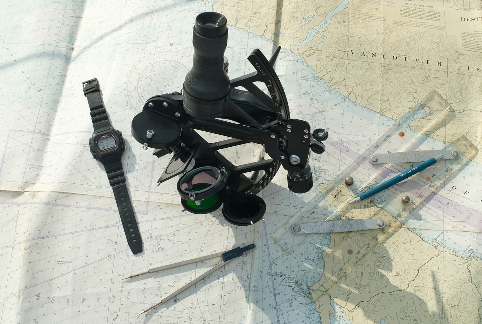 A sextant, watch, dividers and ruler laid out on a nautical chart